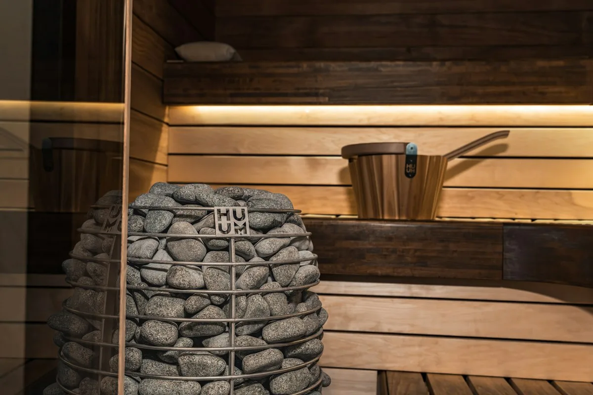 Holzkabine mit Ofen voller Steine und einem Aufgusskübel auf der Bank